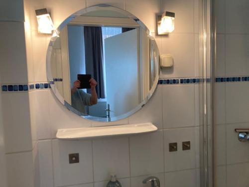 una persona che scatta una foto di uno specchio in bagno di Haus Memel a Niendorf