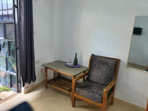 einen Stuhl und einen Tisch mit einer Vase darauf in der Unterkunft Faraja in Meru