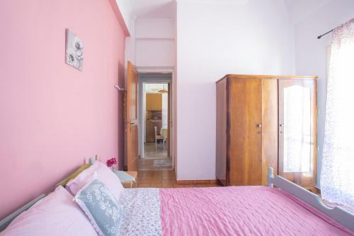 a bedroom with a pink bed with a wooden cabinet at Passiflora Vacation House in Nydri