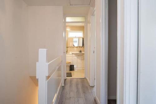 a hallway with white walls and a white staircase at Modern 3 Bedroom house in Finchley in Totteridge