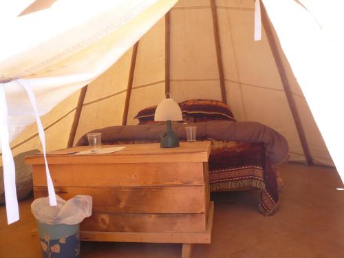 a bedroom with a bed and a table with a lamp at Alpaka-Tipi-Park in Bad Salzungen