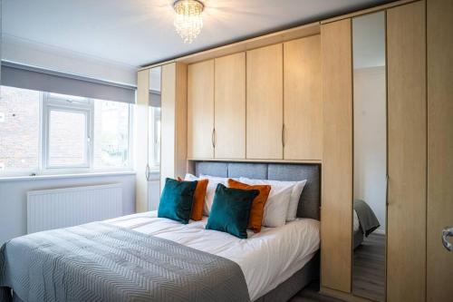 a bedroom with a large bed with blue pillows at Cozy 3 Bedroom house in Finchley in Totteridge