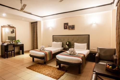 TuraにあるHotel Polo Orchid Turaのベッド2台とデスクが備わるホテルルームです。