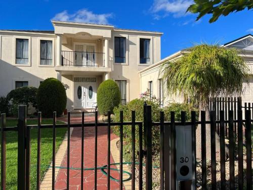 a white house with a fence and a palm tree at Pleasant Private Room in Taylors Lake Near Melbourne Airport in Taylors Lakes