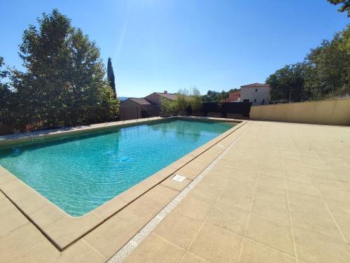 une piscine avec de l'eau bleue dans une cour dans l'établissement Maison Le Jas climatisée - Jardin & Piscine, à Gréoux-les-Bains