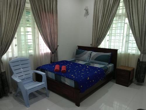 a bedroom with a bed and a chair and windows at Villa Fairuz Hana Islamic Stay in Kangar