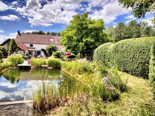 a garden with a pond in front of a house at Tuinkamer in charmante smidse in Zwalm