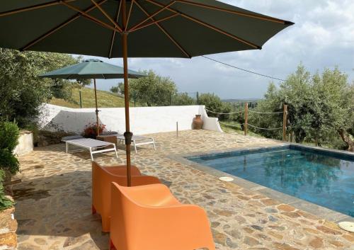a patio with an umbrella and chairs and a pool at Montado Village in Portel