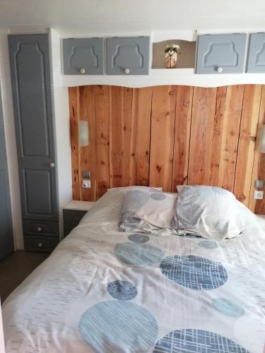 - une chambre avec un grand lit et des murs en bois dans l'établissement grand mobil home domaine La Lande, à Mimizan