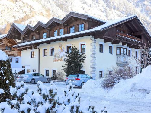 ein großes Gebäude mit zwei Autos im Schnee in der Unterkunft Spacious Apartment in L ngenfeld with Sauna in Huben