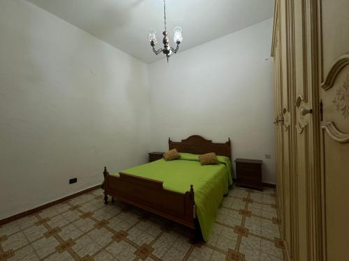 1 dormitorio con 1 cama con manta verde en PM 12 Via Umberto Primo Guest House, en Torpè