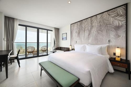 a bedroom with a large white bed and a desk at Emerald Ho Tram Resort in Ho Tram