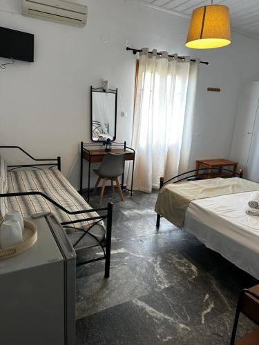 een slaapkamer met 2 bedden en een bureau met een spiegel bij KIRIKOS ROOMS in Sifnos