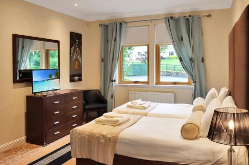 a bedroom with two beds and a television at Lodges by Atholl Palace in Pitlochry