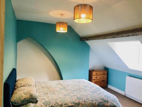 a bedroom with blue walls and a bed and two lights at Llangollen Townhouse 4 bedroom in Llangollen
