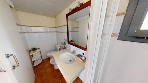 a bathroom with a sink and a toilet and a mirror at Citronella in L'Ampolla