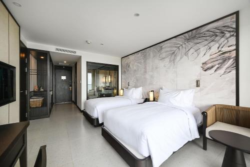 two beds in a hotel room with a large wall at Emerald Ho Tram Resort in Ho Tram