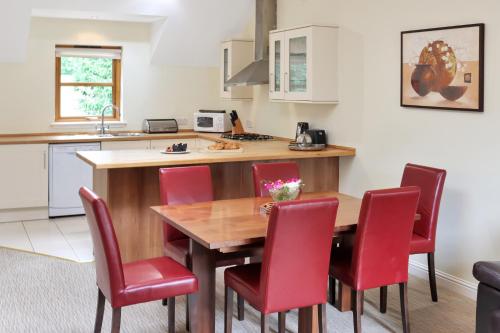 a kitchen with a wooden table and red chairs at Lodges by Atholl Palace in Pitlochry