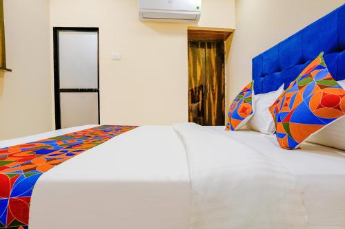 a bedroom with two white beds with colorful pillows at FabExpress Kurla Inn - Nr BKC in Mumbai