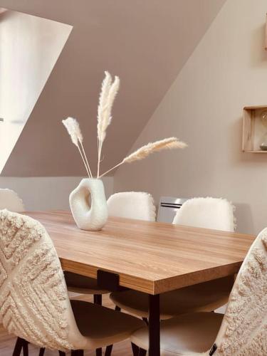 a dining room table with chairs and a vase with feathers at Cocon Bohème & Travertin in Joigny