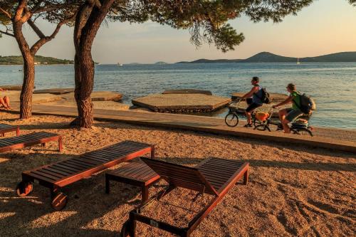 a couple of people riding a bike on the beach at Apartments and Rooms Bozena in Vodice
