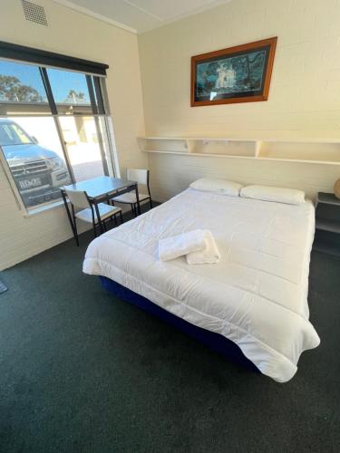 Un dormitorio con una cama y una mesa con un coche al aire libre en Bairnsdale Town Central Motel en Bairnsdale