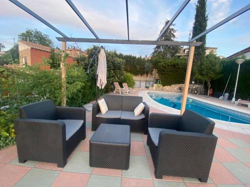 un patio con 2 sillas y una piscina en El Mirador de Santiago en Monachil