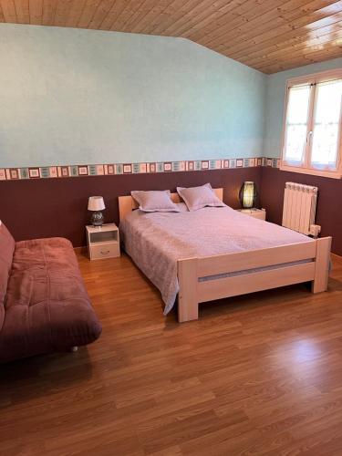 een slaapkamer met een groot bed en een houten vloer bij CHARMANT LOGEMENT ENTIER A LA CAMPAGNE in Sencenac-Puy-de-Fourches