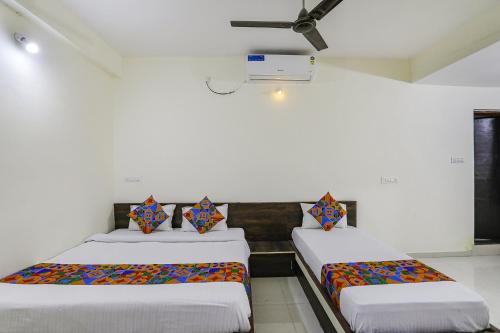 2 letti in una camera con pareti bianche di FabExpress Park View a Rāipur