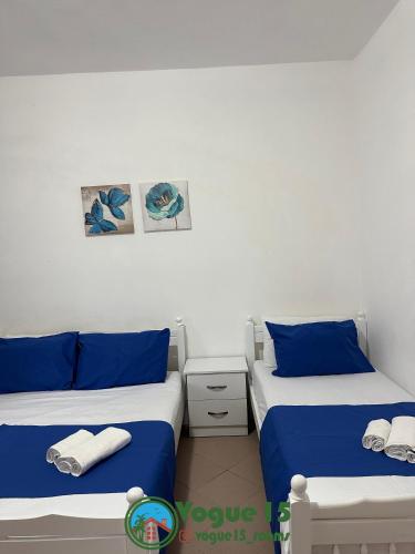 two beds in a room with blue and white at Vogue Rooms in Golem