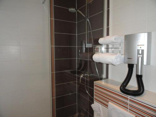 a bathroom with a blow dryer on the wall at The Originals City, Hôtel Continental, Poitiers in Poitiers