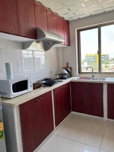 a kitchen with red cabinets and a microwave and a sink at HAYDEN HOME in Libreville