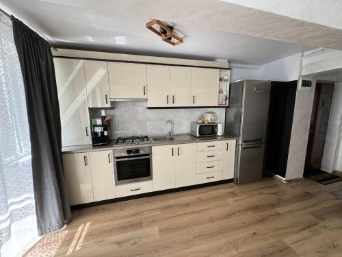 a kitchen with white cabinets and a stainless steel refrigerator at Pretty Luxury Apartament's in Cluj-Napoca