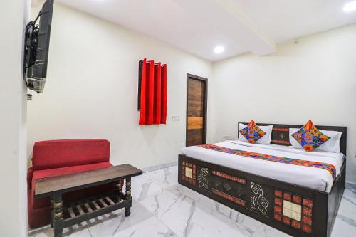 ein Schlafzimmer mit einem Bett und einem roten Stuhl in der Unterkunft FabExpress King Stay in Neu-Delhi