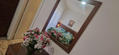a mirror reflecting a room with a couch and flowers at Hotel Dora in Levanto