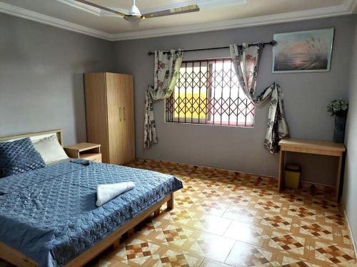 - une chambre avec un lit bleu et une fenêtre dans l'établissement Kim's Guest House, à Kasoa