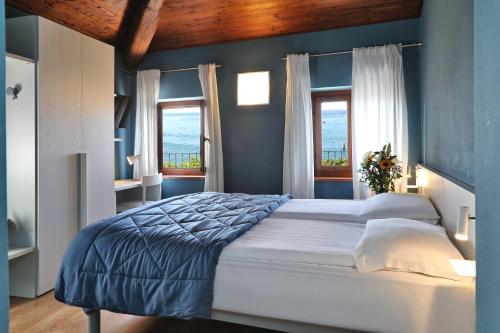 a bedroom with a bed with blue walls and windows at Albergo All'Ancora in Garda