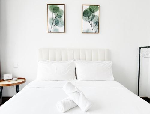a bedroom with a white bed with two pictures on the wall at Riverson SOHO Kota Kinabalu in Kota Kinabalu