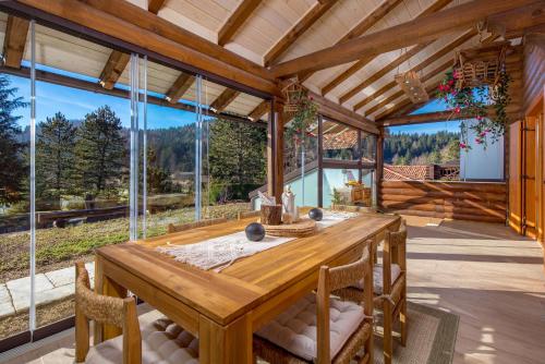 a dining room with a wooden table and glass windows at Kuća DORINE in Fužine