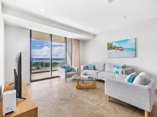 a living room with a couch and a tv at Sweeping Ocean view Apt w Carpark and rooftop pool in Gold Coast
