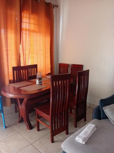 a dining room with a wooden table and four chairs at NEW VILLA TWO ROOMS KANOMBE in Kigali