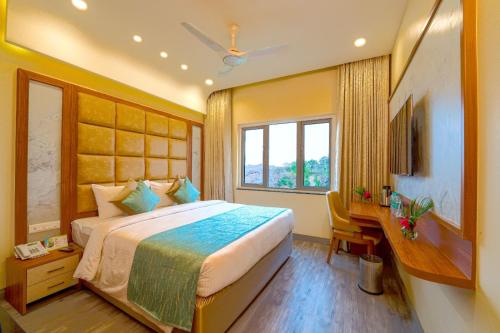 a bedroom with a bed and a desk and a window at Ramoji Film City- Tara Comfort Hotel in Pedda Ambarpet