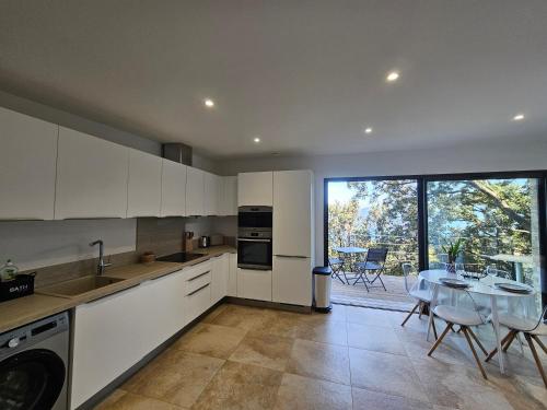 une cuisine avec des armoires blanches et une table avec des chaises dans l'établissement U Paradisu, à Piana