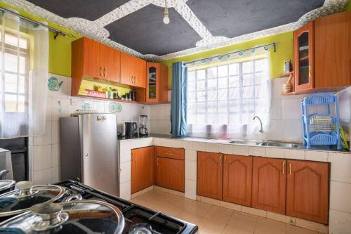 eine Küche mit Holzschränken und einem Kühlschrank aus Edelstahl in der Unterkunft Spacious 2-BR Apartment In Membley in Ruiru