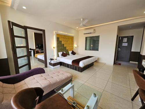 a hotel room with two beds and a couch at Hotel Grand Darshan Vadodara in Vadodara