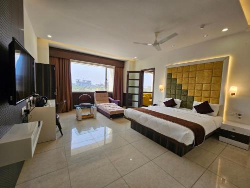 um quarto de hotel com uma cama grande e uma televisão em Hotel Grand Darshan Vadodara em Vadodara