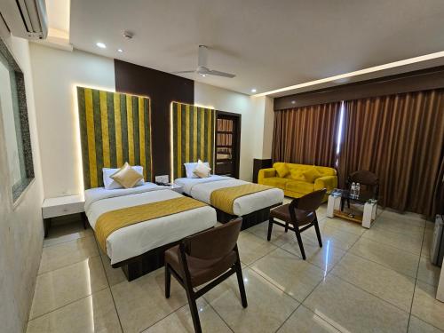 a hotel room with two beds and a yellow couch at Hotel Grand Darshan Vadodara in Vadodara