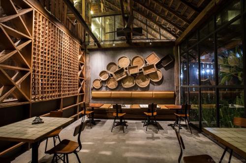 a room with tables and chairs and a wall with logs at Ngeeb bed and EV station in Chiang Rai