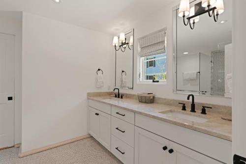 un bagno bianco con due lavandini e uno specchio di Park Cottage - 609 Oak Street a Demere Park