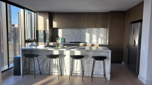 a kitchen with a marble counter and bar stools at Paragon Apartment Penthouse Amazing Views, Spacious & Great Location in Melbourne